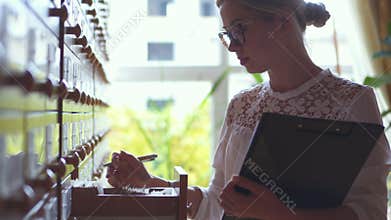 Librarian flipping through cards and taking note at the library