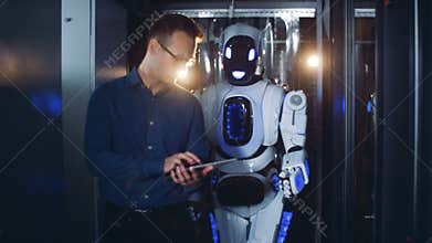 Human-like droid is being guided by a walking male expert