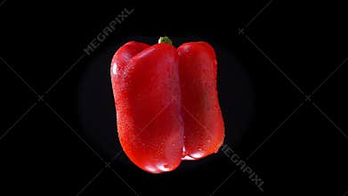 Red bell pepper twisting around fastly on black background.