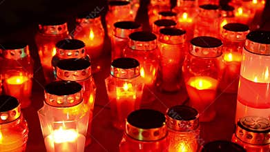 A lot of colorful candles burning at cemetery at night. Votive candles glows on grave. All saints day. Prayer lighted candles in a