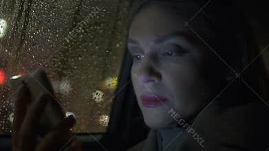 Thoughtful lady in taxi reading book on smartphone, online application, chatting