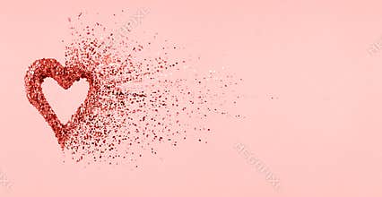 Glitter heart dissolving into pieces on pink background. Valentines day, broken heart and love emergence concept . Living coral
