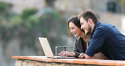 Happy couple typing on a laptop searching content