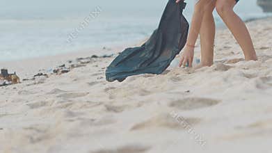 Closeup of volunteer picking up plastic bottle on the white ocean beach. Volunteer cleaning the beach. Tidying up