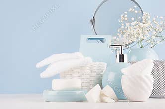 Dressing table with circle mirror, cosmetic silver accessories and white small flowers in ceramic pastel blue vase on white wood.