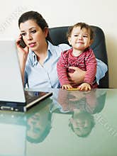 Businesswoman on the phone, holding daughter