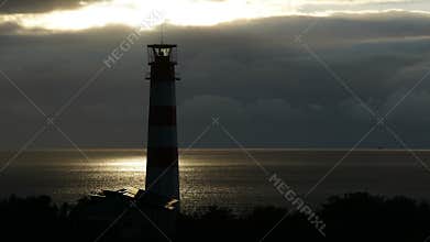 Lighthouse on the sea under stormy clouds and with the ship in the background