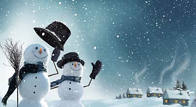 Two snowmen standing in winter Christmas landscape.