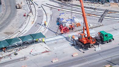 Unloading concrete plates from truck by crane at road construction site timelapse.