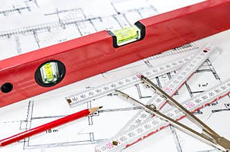 Spirit level and other measurement equipment lying on generic building plan