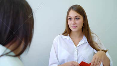 Young female students taking color cards and discussing assignment in high school classroom
