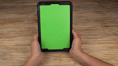 A woman holds a tablet PC with a green screen for your own custom content.