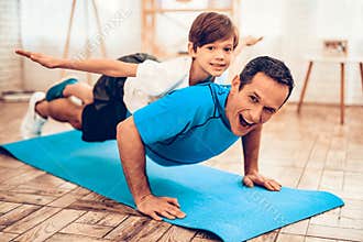 Boy Liying Fathers Back Doing Push Ups on Mat.