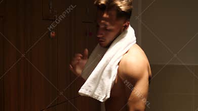 Shirtless muscular young male athlete in gym dressing room