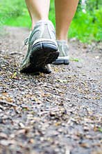 Woman walking on trail in forest, sport shoes