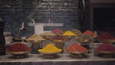 Different kinds of seasonings on the counter of the store in metal bowls. Variety of spices and herbs on the table