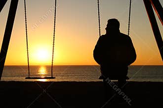 Man alone on a swing looking at empty seat