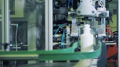 Bottoms of white plastic bottles are getting cut by the mechanism