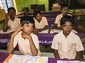Group of children friends classmates studying with book sitting on chairs indoors at the school. School kids enjoying friendship
