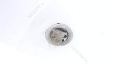 Water is drawn into the bath with hair in the drain hole of the bath, the water gurgles and rotates. Female hand pulls a