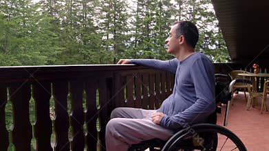 Young man in wheelchair relaxing on terrace