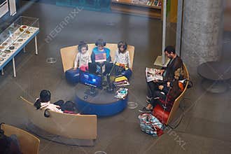 Montreal, Quebec, Canada, September 29, 2018: Man reading a newspaper and the children watch animated cartoonin one of the rooms