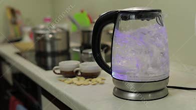Tea kettle with boiling water. Tea bags and sugar on the background