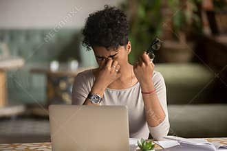 Overworked tired african woman holding glasses feel eye strain
