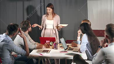 Female specialist is presenting her report in meeting, in front her colleagues