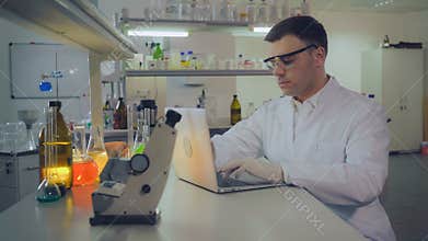 Doctor typing on computer entering results after research.