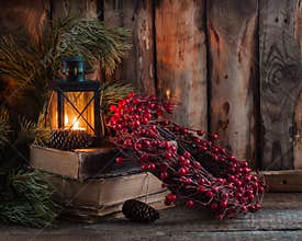 Christmas wreath with berries on old books with a lantern on wooden background