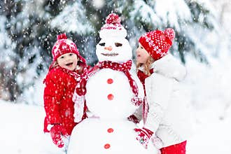 Kids building snowman. Children in snow. Winter fun.