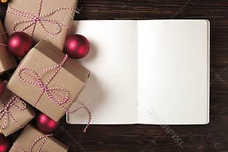 Notebook with christmas decoration and gifts on wooden background. To do list, santa letter concept. Top view, flat lay, text spac