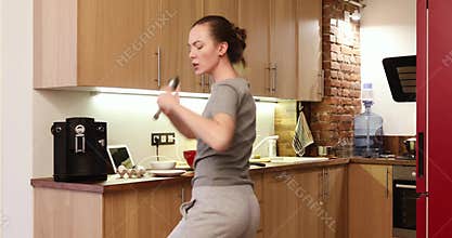 Happy woman in the kitchen sings and dances