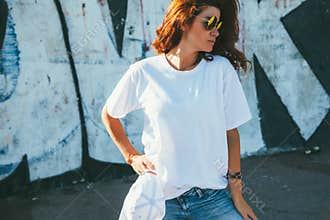 Model wearing plain tshirt and sunglasses posing over street wall