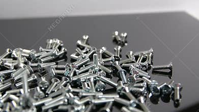 Heap of bolts, screws and nuts falling on neutral background