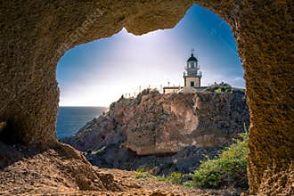 Lighthouse at Akrotiri through a frame of a window of a cave, Santorini.