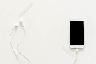 Creative flat lay photo of workspace desk with earphones and mobile phone with blank screen on copy space white background.