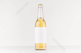 Transparent longneck beer bottle 500ml with blank white label on white wooden board, mock up.