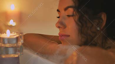 Beautiful woman in the bath by the candlelight