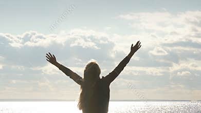 Girl on the beach raises his arms to the sky