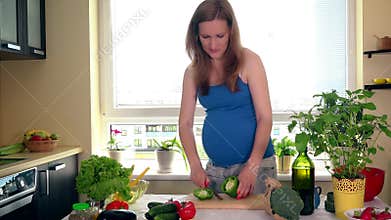 Pregnancy and nutrition. Pregnant woman cut paprika vegetables on kitchen table