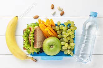 Blue lunch box with healthy food for school children with bottle of water on white wooden background.