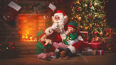 Christmas. Santa Claus with Elves Drink Milk and Eat Cookies