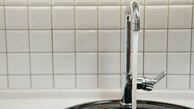 Clean water flows from silver tap in bathroom indoors.