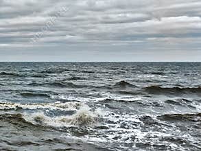 Choppy atlantic ocean waves with surf and grey winter clouds