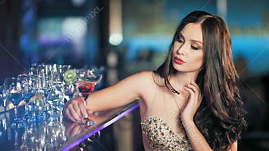 Beauty young brunette woman sitting at the bar with glass of wine in luxury interior