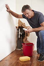 Middle aged man with a burst pipe dialling phone for help