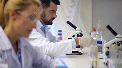 Mature scientist chatting with colleague while examining sample in laboratory