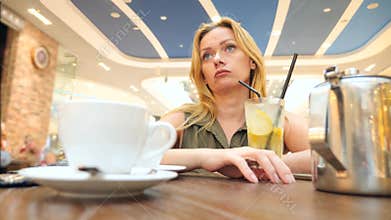 Sad woman waiting for someone in cafe and drinking tea. 4k, slow-motion, close-up, copy space